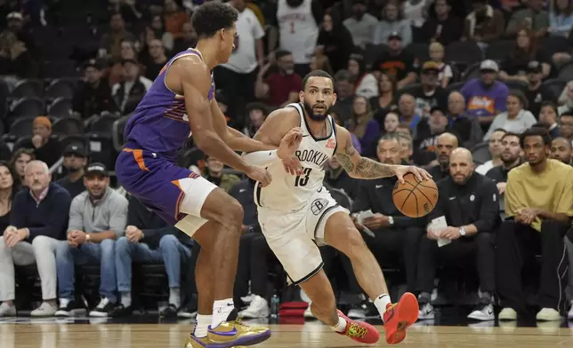 Brooklyn Nets guard Tyrese Martin (13) drive on Phoenix Suns center Oso Ighodaro during the first half of an NBA basketball game, Wednesday, Nov. 27, 2024, in Phoenix. (AP Photo/Rick Scuteri)