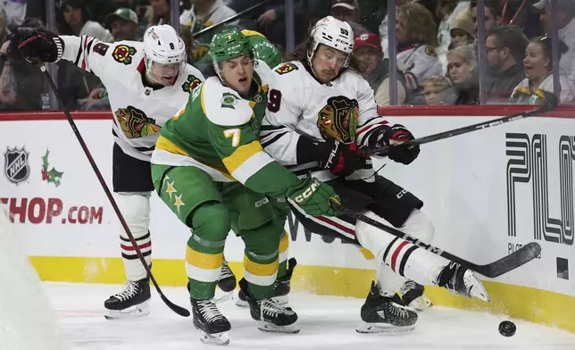 Minnesota Wild defenseman Brock Faber (7) and Chicago Blackhawks left wing Tyler Bertuzzi (59) battle for the puck during the second period of an NHL hockey game, Friday, Nov. 29, 2024, in St. Paul, Minn. (AP Photo/Ellen Schmidt)