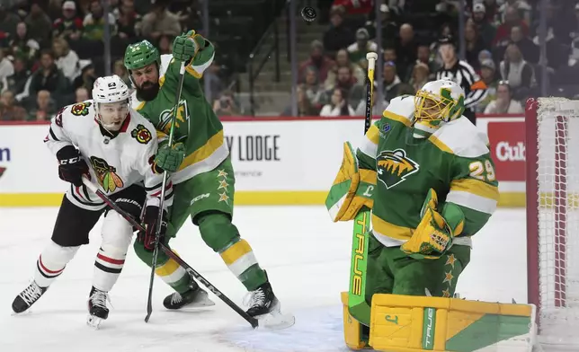 Minnesota Wild goaltender Marc-Andre Fleury (29) saves the puck while Chicago Blackhawks center Philipp Kurashev (23) and Wild defenseman Zach Bogosian (24) battle near the net during the second period of an NHL hockey game, Friday, Nov. 29, 2024, in St. Paul, Minn. (AP Photo/Ellen Schmidt)