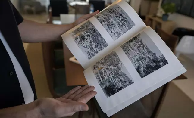 Lubnan Baalbaki shows pictures of Odeisseh village taken by his late father, during an interview with The Associated Press at his house in Geitawi, Beirut, Lebanon, Thursday, Oct. 31, 2024. (AP Photo/Bilal Hussein)