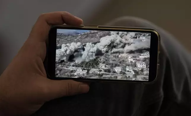 Lubnan Baalbaki shows a video released by the IDF as they blew up his village of Odeiseh during an interview with The Associated Press at his house in Geitawi, Beirut, Lebanon, Thursday, Oct. 31, 2024. (AP Photo/Bilal Hussein)