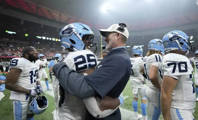 Toronto Argonauts head coach Ryan Dinwiddie, center right, celebrates with teammate Ka'Deem Carey (25) during the second half of a CFL football game at the 111th Grey Cup against the Winnipeg Blue Bombers, in Vancouver, British Columbia, Sunday, Nov. 17, 2024. (Nathan Denette/The Canadian Press via AP)