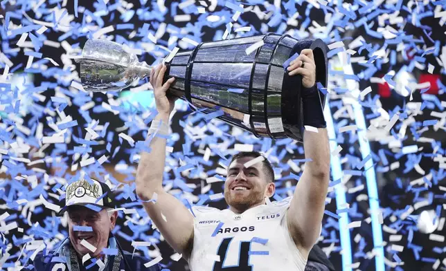 Toronto Argonauts quarterback Nick Arbuckle (4) lifts the Grey Cup after defeating the Winnipeg Blue Bombers in a CFL football game at the 111th Grey Cup in Vancouver, British Columbia, Sunday, Nov. 17, 2024. (Darryl Dyck/The Canadian Press via AP)