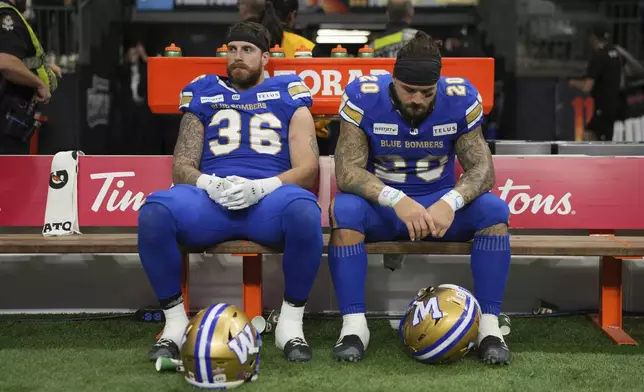 Winnipeg Blue Bombers' Bailey Feltmate (36) and teammate Brady Oliveira (20) sit on the bench after losing the 111th Grey Cup to the Toronto Argonauts, in Vancouver, British Columbia, Sunday, Nov. 17, 2024. (Ethan Cairns/The Canadian Press via AP)