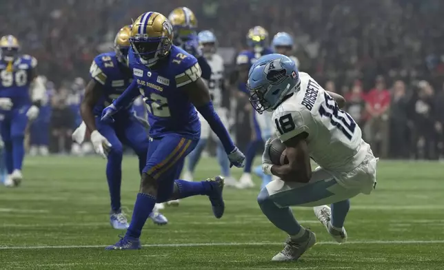 Toronto Argonauts' Dejon Brissett (18) scores a touchdown as Winnipeg Blue Bombers' Nick Taylor (12) looks on during the second half of a CFL football game at the 111th Grey Cup in Vancouver, British Columbia, Sunday, Nov. 17, 2024. (Ethan Cairns/The Canadian Press via AP)