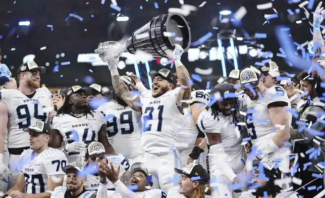 Toronto Argonauts' Daniel Adeboboye (21) lifts the Grey Cup after defeating the Winnipeg Blue Bombers in a CFL football game at the 111th Grey Cup in Vancouver, British Columbia, Sunday, Nov. 17, 2024. (Darryl Dyck/The Canadian Press via AP)