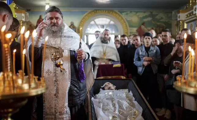 FILE - A priest reads a prayer for a fallen Ukrainian solfer fIhor Kusochek during the funeral ceremony in Bobrovytsia, Chernihiv region, Ukraine, on Oct. 4, 2024. (AP Photo/Evgeniy Maloletka, File)