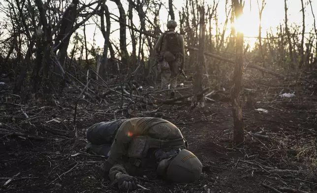 FILE - A Ukrainian assault unit commander passes by a dead Russian soldier on the front line near Andriivka, Ukraine, Saturday, Sept. 16, 2023. (AP Photo/Alex Babenko, File)