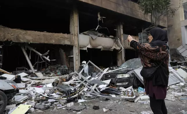 A woman uses her phone to record destroyed shops that were hit Sunday evening by an Israeli airstrike in central Beirut, Lebanon, Monday, Nov. 18, 2024. (AP Photo/Hussein Malla)