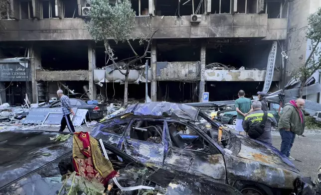 People gather in front of destroyed shops that were hit Sunday evening in an Israeli airstrike in central Beirut, Lebanon, Monday, Nov. 18, 2024. (AP Photo/Hussein Malla)