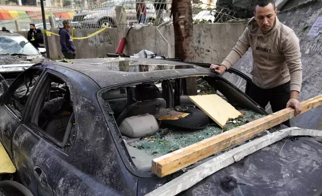 A man removes debris from his damaged car at the site where an Israeli airstrike on Sunday evening hit in central Beirut, Lebanon, Monday, Nov. 18, 2024. (AP Photo/Hussein Malla)