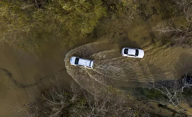 A car drives through floodwater at the Billing Aquadrome in Northamptonshire, England, Monday Nov. 25, 2024, after Storm Bert caused "devastating" flooding over the weekend. (Jordan Pettitt/PA via AP)