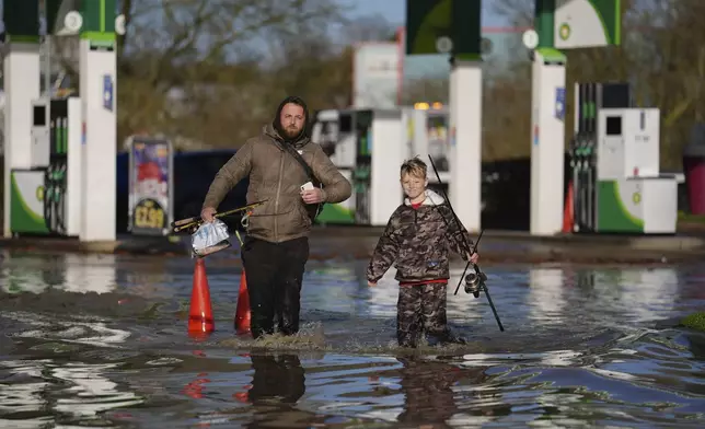 People walk through floodwater near the Billing Aquadrome in Northamptonshire, England, Monday Nov. 25, 2024, after Storm Bert caused "devastating" flooding over the weekend. (Jordan Pettitt/PA via AP)