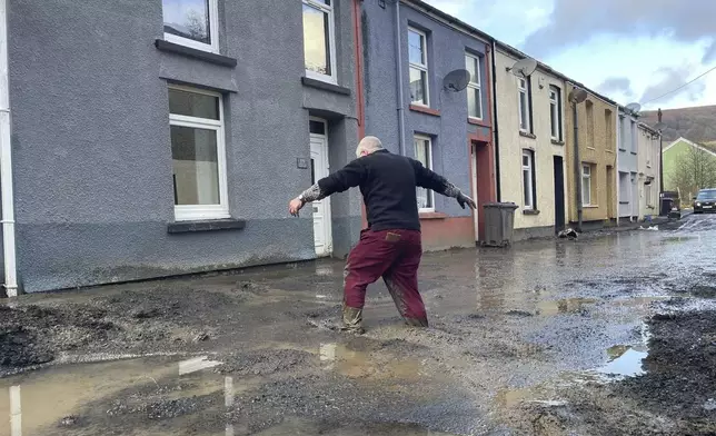 Rob, surname not given, walks through flood water as an apparent mud slide has forced people from their homes as Storm Bert continues to cause disruption, in Cwmtillery, Wales, Monday, Nov. 25, 2024. (George Thompson/PA via AP)