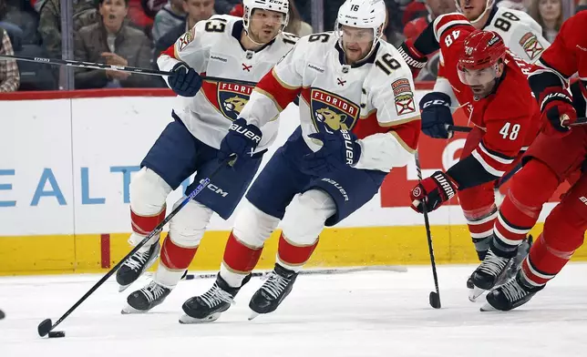 Florida Panthers' Aleksander Barkov (16) moves the puck away from Carolina Hurricanes' Jordan Martinook (48) during the first period of an NHL hockey game in Raleigh, N.C., Friday, Nov. 29, 2024. (AP Photo/Karl B DeBlaker)