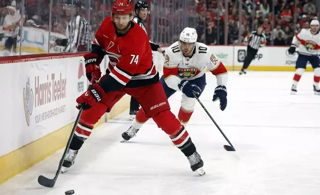 Carolina Hurricanes' Jaccob Slavin (74) goes for the puck in front of Florida Panthers' A.J. Greer (10) during the first period of an NHL hockey game in Raleigh, N.C., Friday, Nov. 29, 2024. (AP Photo/Karl B DeBlaker)