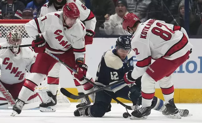 Carolina Hurricanes defenseman Dmitry Orlov, left, Columbus Blue Jackets right wing Kevin Labanc (62) and Hurricanes center Jesperi Kotkaniemi (82) fight for control of the puck in the first period of an NHL hockey game in Columbus, Saturday, Nov. 23, 2024. (AP Photo/Sue Ogrocki)