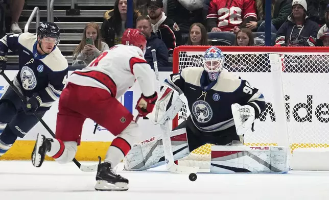 Carolina Hurricanes center Jack Drury, center, skates in on Columbus Blue Jackets goaltender Elvis Merzlikins in the second period of an NHL hockey game in Columbus, Saturday, Nov. 23, 2024. Defenseman Cole Sillinger is at left. (AP Photo/Sue Ogrocki)