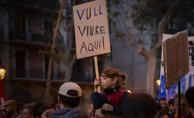 Oscar, 6, holds a sign reading in Catalan "I want to live here" as they protest the skyrocketing cost of renting an apartment in Barcelona, Spain, Saturday, Nov. 23, 2024. (AP Photo/Emilio Morenatti)