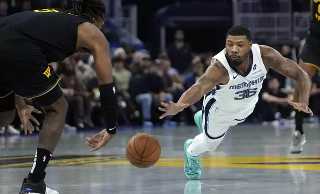 Memphis Grizzlies guard Marcus Smart, right, is unable to take the ball away from Golden State Warriors center Kevon Looney during the first half of an Emirates NBA Cup basketball game Friday, Nov. 15, 2024, in San Francisco. (AP Photo/Godofredo A. Vásquez)