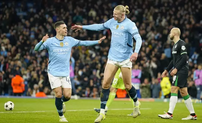 Manchester City's Erling Haaland, center, celebrates with Phil Foden, left, after scoring his side's third goal during the Champions League opening phase soccer match between Manchester City and Feyenoord at the Etihad Stadium in Manchester, England, Tuesday, Nov. 26, 2024. (AP Photo/Dave Thompson)