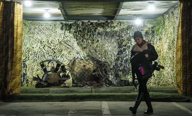 A journalist walks in front of fragments of a rocket which struck Dnipro on November 21, at a center for forensic analysis in undisclosed location, Ukraine, Sunday Nov. 24, 2024. (AP Photo/Evgeniy Maloletka)