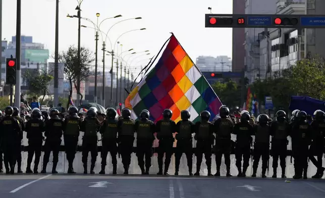 Police officers block anti-government protesters from making their way to Congress, on the sidelines of the Asia-Pacific Economic Cooperation (APEC) summit in Lima, Peru, Wednesday, Nov. 13, 2024. (AP Photo/Fernando Vergara)