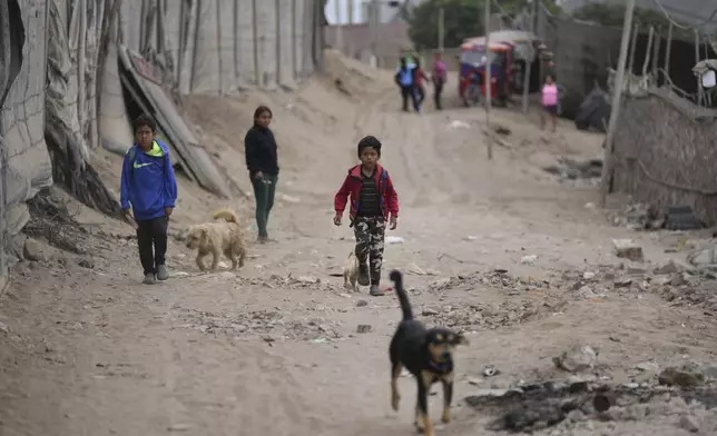 Children walk around in the Senor de la Soledad shantytown near a Chinese-funded port in Chancay, Peru, Tuesday, Nov. 12, 2024. (AP Photo/Silvia Izquierdo)