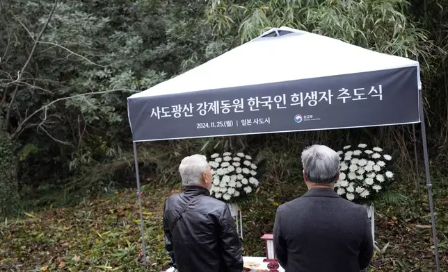 Relatives of Korean victims and South Korean officials offer a prayer during a memorial service at the site of former Fourth Souai Dormitory for the mine workers from the Korean Peninsula, in Sado, Niigata prefecture, Japan, Monday, Nov. 25, 2024, a day after boycotting a memorial organized by Japanese officials. The black banner reads "A memorial service for Korean forced laborer victims at Sado Mine." (AP Photo/Eugene Hoshiko)