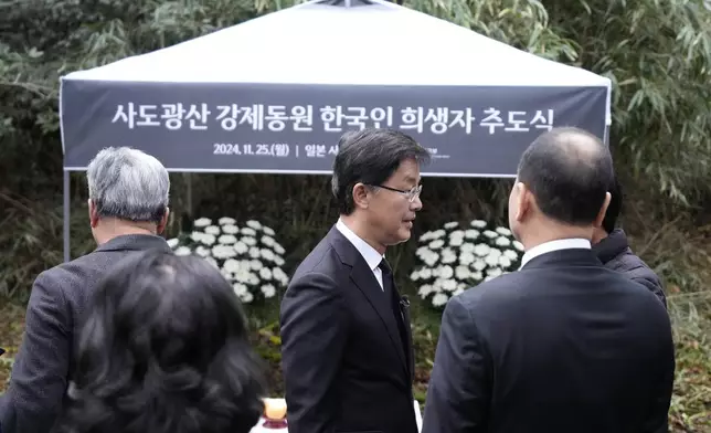 South Korean Ambassador to Japan Park Cheol-hee, center, speaks with the relatives of Korean victims and South Korean officials at the site of former Fourth Souai Dormitory for the mine workers from the Korean Peninsula, after a memorial service in Sado, Niigata prefecture, Japan, Monday, Nov. 25, 2024, a day after boycotting a memorial organized by Japanese officials. The black banner reads "A memorial service for Korean forced laborer victims at Sado Mine." (AP Photo/Eugene Hoshiko)