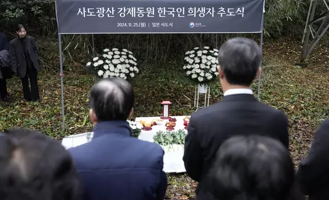 Relatives of Korean victims and South Korean officials offer a prayer during a memorial service at the site of former Fourth Souai Dormitory for the mine workers from the Korean Peninsula, in Sado, Niigata prefecture, Japan, Monday, Nov. 25, 2024, a day after boycotting a memorial organized by Japanese officials. The black banner reads "A memorial service for Korean forced laborer victims at Sado Mine." (AP Photo/Eugene Hoshiko)