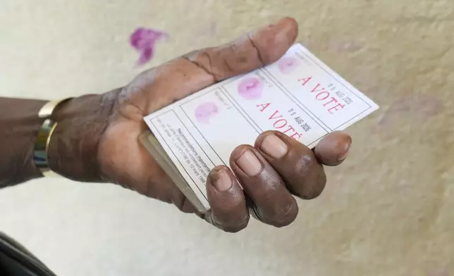 A voter show his stamped electoral card after casting his ballot in a referendum on whether to adopt a new constitution in Libreville, Gabon, Saturday, Nov. 16, 2024. (AP Photo/Betines Makosso)