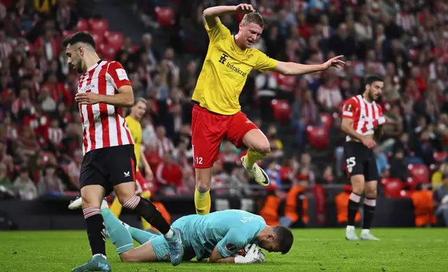 Elfsborg's Emil Holten jumps on Athletic Bilbao's goalkeeper Unai Simon during the Europa League opening phase soccer match between Athletic Bilbao and Elfsborg at the San Mames stadium in Bilbao, Spain, Thursday, Nov. 28, 2024. (AP Photo/Miguel Oses)