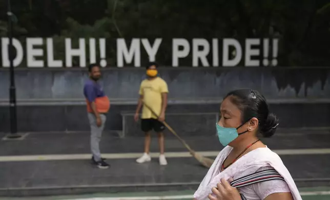 A woman wearing a face mask walks on a street in New Delhi, India, Thursday, Nov. 14, 2024. (AP Photo/Manish Swarup)