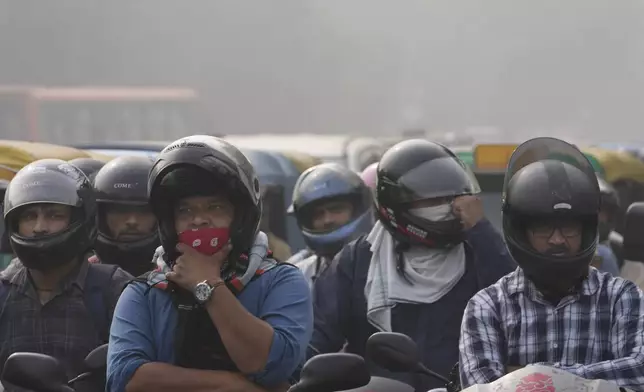 Commuters wait at a traffic signal surrounded by smog in New Delhi, India, Thursday, Nov. 14, 2024. (AP Photo/Manish Swarup)