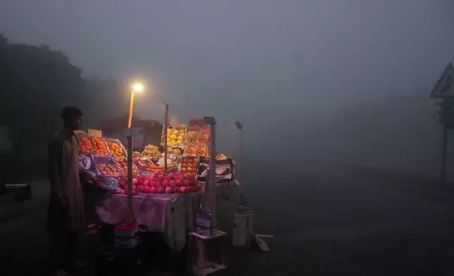 A fruit seller arranges his stall in early morning as smog envelopes the area of Lahore, Pakistan, Thursday, Nov. 14, 2024. (AP Photo/K.M. Chaudary)