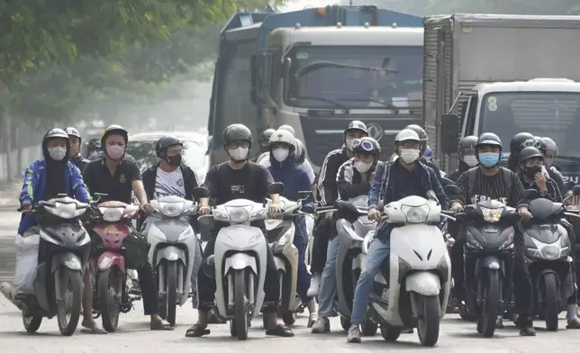 People wearing face masks wait at a traffic signal in Hanoi, Vietnam, Thursday Nov. 14, 2024. (AP Photo/Hau Dinh)