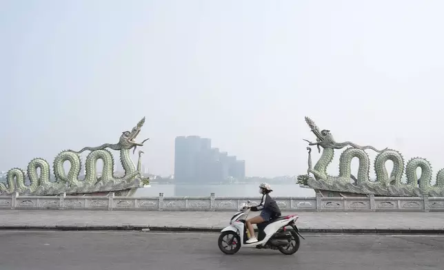 A woman wearing a face mask rides under a hazy sky in Hanoi, Vietnam, Thursday Nov. 14, 2024. (AP Photo/Hau Dinh)