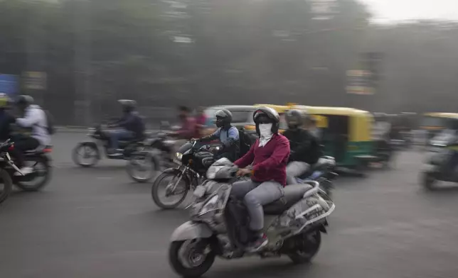 A commuter wearing a mask rides on a road enveloped by smog in New Delhi, India, Thursday, Nov. 14, 2024. (AP Photo/Manish Swarup)