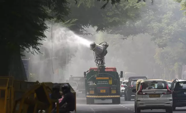 A Delhi government vehicle sprinkles water to control air pollution as a thick layer of smog envelops the city, New Delhi, India, Thursday, Nov. 14, 2024. (AP Photo/Manish Swarup)