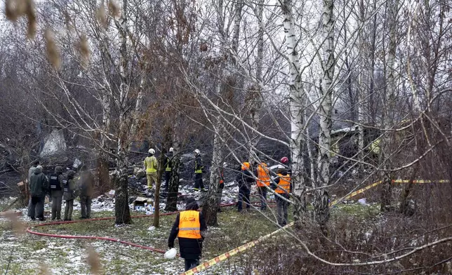 Lithuanian Emergency Ministry employees work near the place where a DHL cargo plane crashed into a house near the Lithuanian capital Vilnius, Lithuania, Monday, Nov. 25, 2024. (AP Photo/Mindaugas Kulbis)