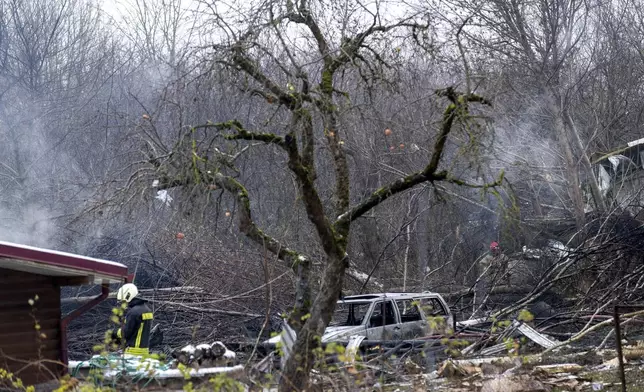 Lithuanian Emergency Ministry employees work near the place where a DHL cargo plane crashed into a house near the Lithuanian capital Vilnius, Lithuania, Monday, Nov. 25, 2024. (AP Photo/Mindaugas Kulbis)