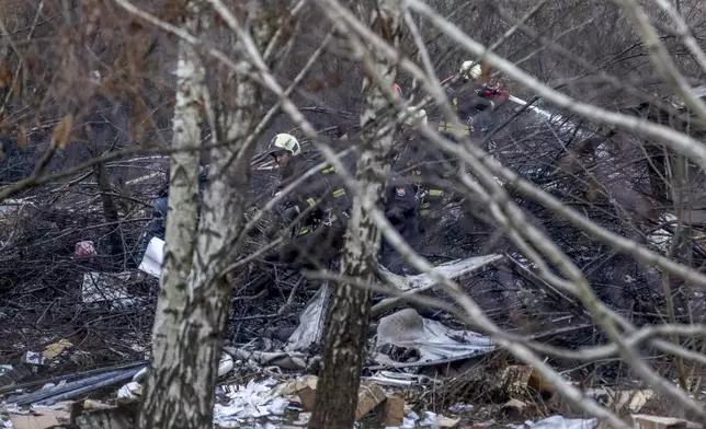 Lithuanian emergency personnel work by parts of the wreckage of a DHL cargo plane which crashed into a house near the Lithuanian capital Vilnius, Lithuania, Monday, Nov. 25, 2024. (AP Photo/Mindaugas Kulbis)