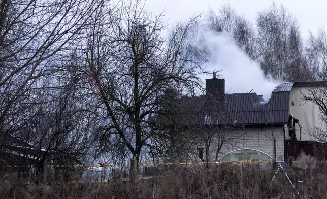 A smoke rises from the place where a DHL cargo plane crashed into a house near the Lithuanian capital Vilnius, Lithuania, Lithuania, Monday, Nov. 25, 2024. (AP Photo/Mindaugas Kulbis)