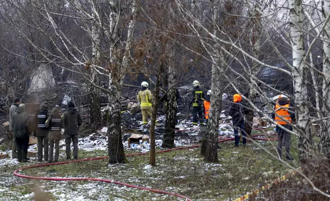 Lithuanian Emergency Ministry employees work near the place where a DHL cargo plane crashed into a house near the Lithuanian capital Vilnius, Lithuania, Lithuania, Monday, Nov. 25, 2024. (AP Photo/Mindaugas Kulbis)