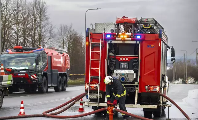 Lithuanian emergency personnel prepare to work near the site where a DHL cargo plane crashed into a house near Vilnius, Lithuania, Monday, Nov. 25, 2024. (AP Photo/Mindaugas Kulbis)