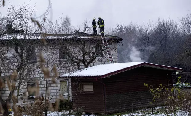 Lithuanian Emergency Ministry employees work near the place where a DHL cargo plane crashed into a house near the Lithuanian capital Vilnius, Lithuania, Lithuania, Monday, Nov. 25, 2024. (AP Photo/Mindaugas Kulbis)