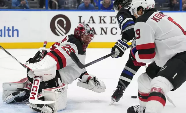 New Jersey Devils goaltender Jacob Markstrom (25) stops a shot by Tampa Bay Lightning center Jake Guentzel (59) during the second period of an NHL hockey game Saturday, Nov. 16, 2024, in Tampa, Fla. (AP Photo/Chris O'Meara)