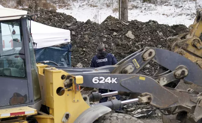 An employee of the coroner's office walks the scene, Friday, Dec. 6, 2024, where Elizabeth Pollard is believed to have disappeared in a sinkhole while looking for her cat, in Marguerite, Pa. (AP Photo/Matt Freed)
