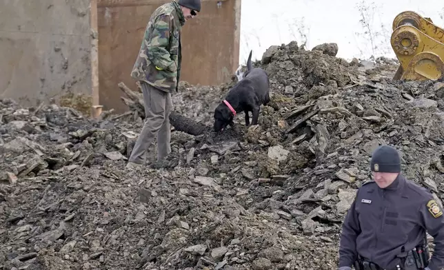 A rescue dog searches though debris that was removed from a sinkhole, Thursday, Dec. 5, 2024, where rescue workers believe Elizabeth Pollard disappeared into while looking for her cat, in Marguerite, Pa. (AP Photo/Matt Freed)